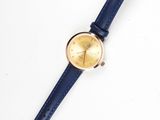 gros plan d'une montre sur une surface blanche avec un bracelet bleu