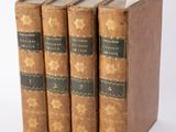 trois vieux livres posés l'un sur l'autre sur une surface blanche