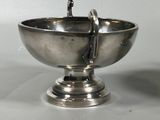 a silver bowl with a spoon in it sitting on a table