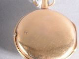 a gold pocket watch hanging from a white string
