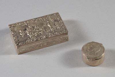une petite boîte en argent et une pièce de monnaie posées sur une table