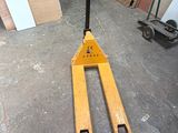 a fork lifter sitting in a garage next to a pile of wood
