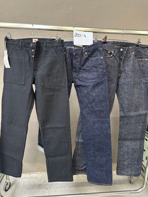 trois paires de jeans suspendues à un portant dans un magasin