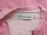 pink jacket with christian dior label on it sitting on a bed