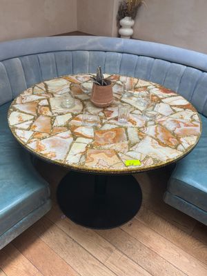 une table ronde avec un plateau en marbre posée sur un banc bleu