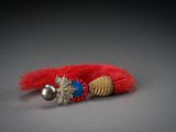 a close up of a red and gold bracelet with a bell on it