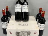 quatre bouteilles de vin rouge sont posées dans une vitrine posée sur une table