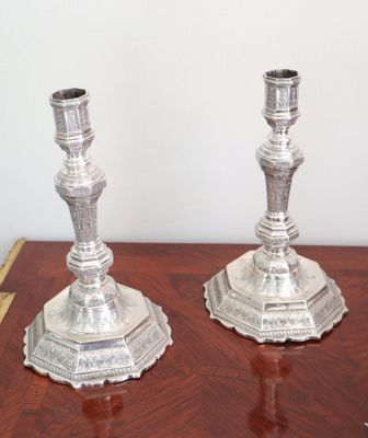 two silver candlesticks sitting on a wooden table