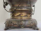 a bronze vase with a chain around it on a table