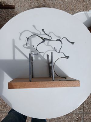 une sculpture représentant des ciseaux, posée sur une étagère posée sur une table