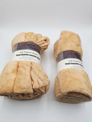 deux rouleaux de couvertures marron posés sur une surface blanche