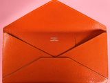 an orange envelope with a small card inside on a pink background
