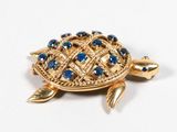 a gold turtle brooch with blue stones on it
