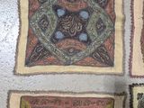 four square rugs on the floor with a person standing in front of them