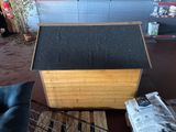 a dog house made out of wood with a black roof