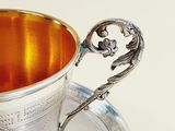 a silver cup with a handle on a silver plate