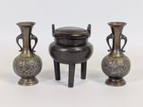 trois vases en métal munis d'anses, placés les uns à côté des autres