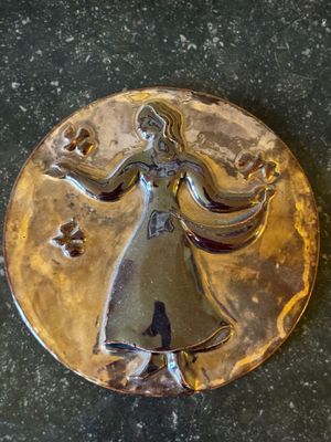 une image représentant une assiette en or sur laquelle figure une femme