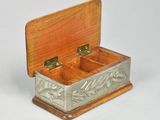 a small wooden box with a metal lid on a white surface