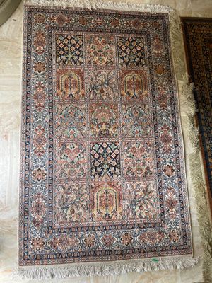 un grand tapis oriental posé sur un parquet, près d'un mur