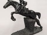 une statue représentant un homme à cheval en train de sauter par-dessus un rocher
