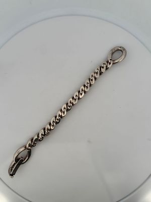 a close up of a silver bracelet on a white plate