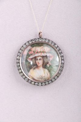un gros plan sur un collier orné de la photo d'une femme portant un chapeau
