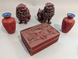trois vases rouges posés les uns à côté des autres sur une table