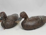 deux canards en bois posés l'un sur l'autre sur une surface blanche