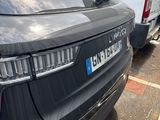 a black car parked in a parking lot next to a white van