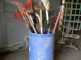 many utensils and spoons in a bucket in a garage