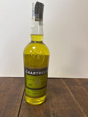 une photo d'une bouteille de Chartreuse posée sur une table en bois