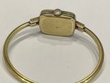 a close up of a gold bracelet with a square clasp