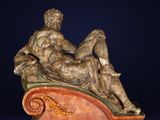 statue d'un homme allongé sur un banc, sur fond bleu foncé