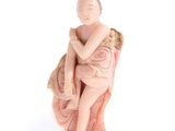 figurine représentant une femme assise sur une chaise, les bras croisés