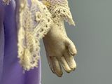 a close up of a doll ' s hand with lace on it