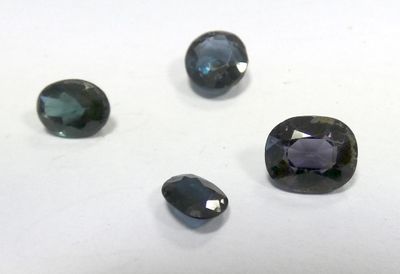 four different colored gems are arranged on a white surface