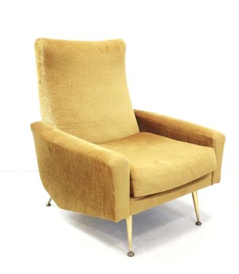 beige upholstered chair with metal legs and arm rests against a white wall