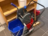 a mop and bucket on the floor next to a shelf