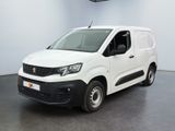 La camionnette blanche est garée dans une grande pièce au sol noir.