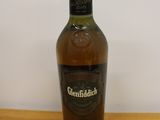 the bottle of whisky is sitting on the table next to the glass