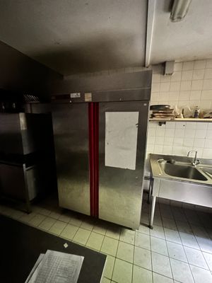 une cuisine faiblement éclairée, équipée d'appareils électroménagers en inox et d'un évier