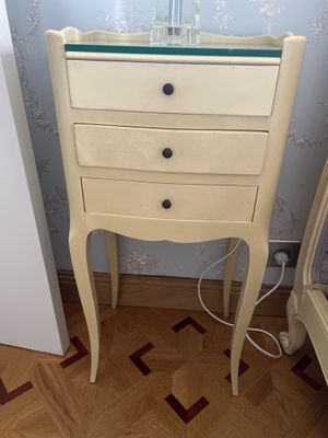 une petite table sur laquelle est posé un vase, à côté d'un lit