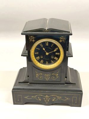 a black and gold clock with a book on top of it