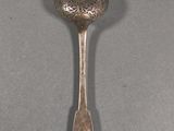 silver spoon with a flower design on it on a gray surface