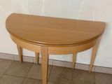 une table en bois au plateau incurvé, posée sur un sol carrelé