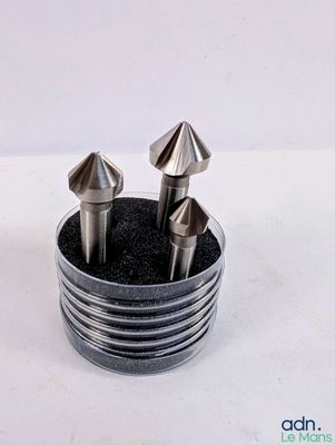 quatre pièces métalliques se trouvent dans un support métallique posé sur une surface blanche