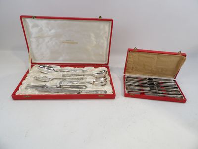 un assortiment d'argenterie dans un coffret rouge posé sur une surface blanche