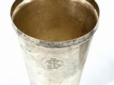 a silver cup that is sitting on a white surface