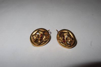pair of gold tone earrings with red stones on them